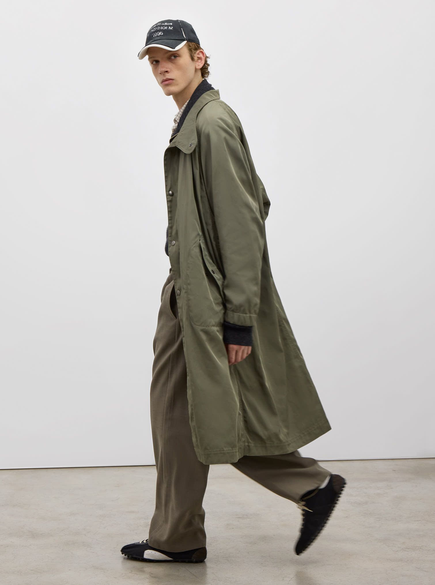 Men look with polyester green trench, green pants, baseball cap and black low sneakers