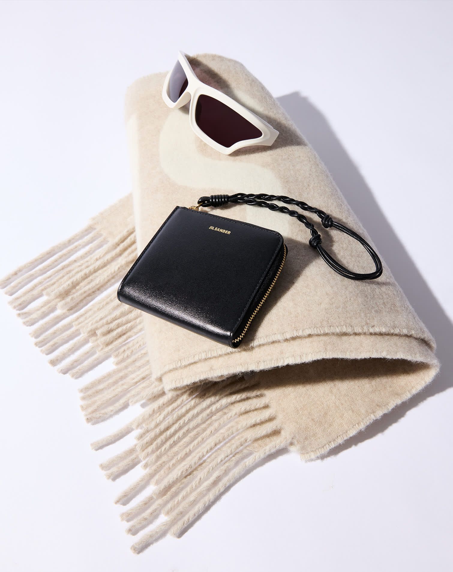 Beige fringe trim scarf with white slim sunglasses and black leather wallet with wrist strap