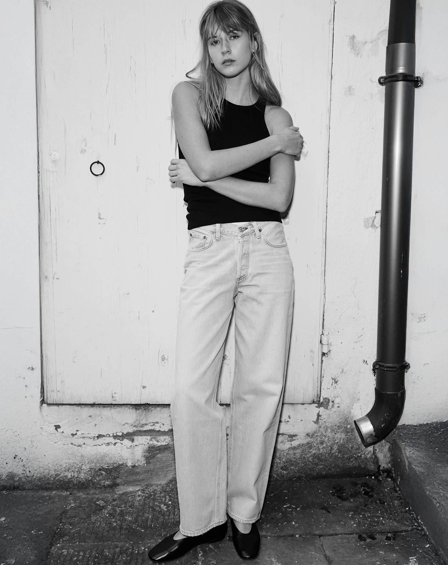 Woman wears casual outfit of black sleeveless top and white denim.