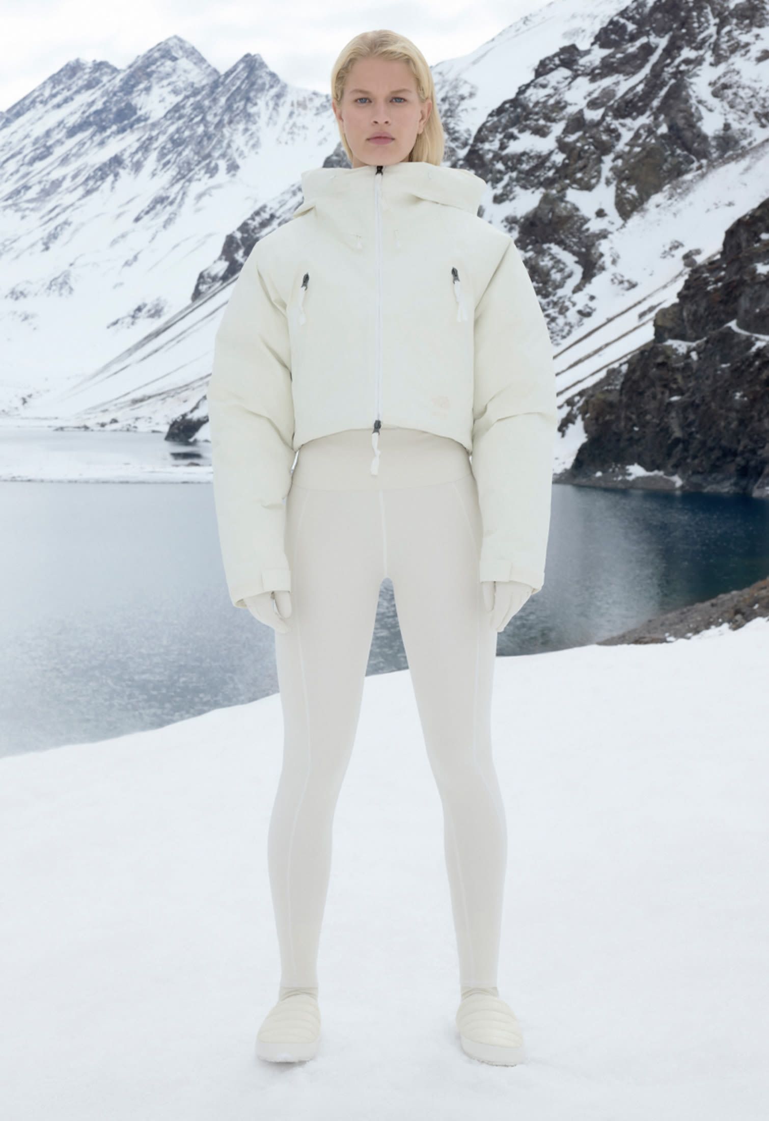 Model poses at the mountain in skiing outfit The North Face x Skims with insulated jacket, Thermoball Mules and leggings
